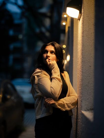 A thoughtful, upward-looking pose. The warm light from the wall sconces creates a beautiful, soft illumination on her face.