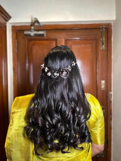 A close-up of the back, showing the intricate braid and the delicate pink floral hairpiece. This is a romantic choice for an engagement.