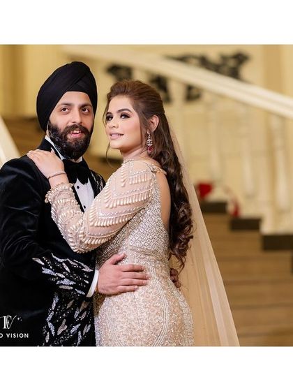 A stylish portrait of the couple against a grand staircase, showcasing the bride's beautiful gown and the groom's sharp tuxedo.