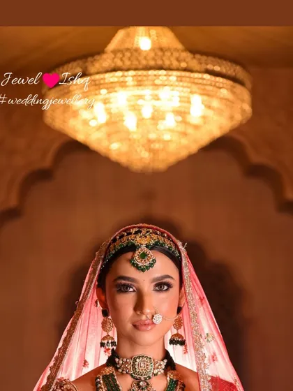A creative shot looking up at the bride under a grand chandelier. The jewellery gleams, showcasing its regal quality.