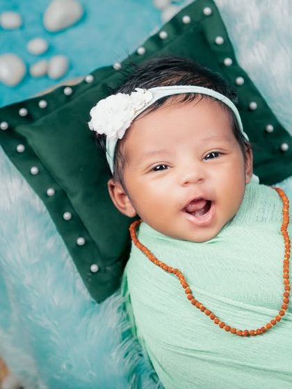 A sweet, smiling newborn enjoys the Maha Shivratri theme. This close-up shot captures an awake and happy baby, showing that we can capture beautiful expressions even when they aren't asleep.