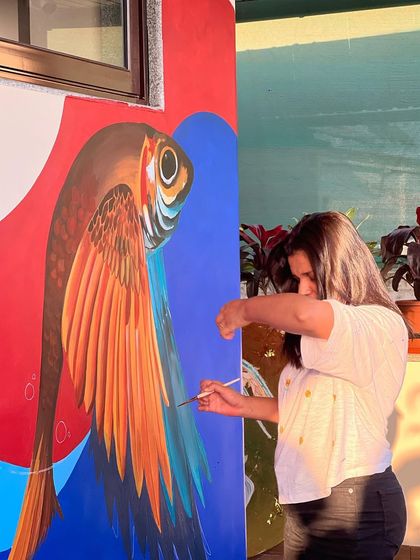 Painting the surreal winged fish mural in Goa. The golden hour light adds a magical glow to the process, reflecting the dreamlike quality of the artwork itself.