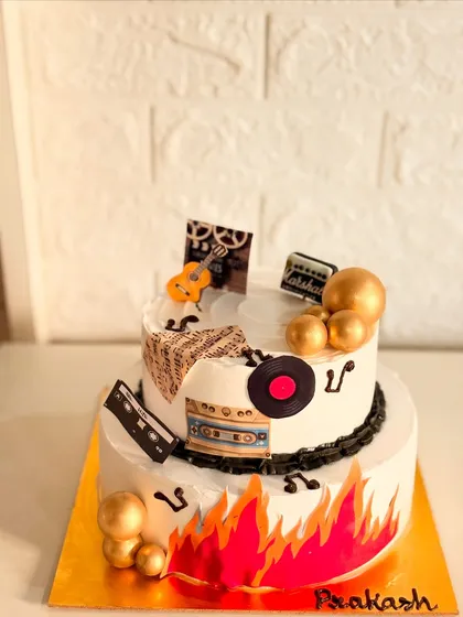 A two-tier Tiramisu-flavored cake with a retro music theme. It's decorated with a vinyl record, cassette tape, and musical notes for a true music lover.