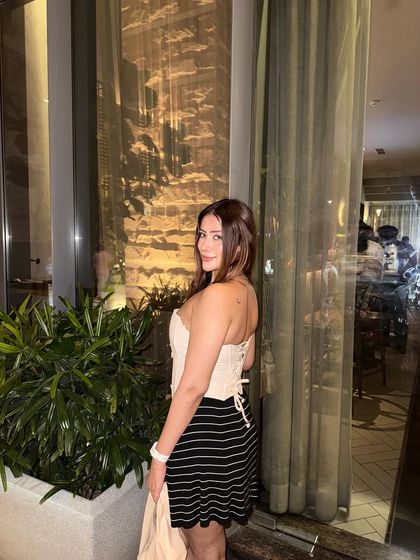 A strapless beige corset top paired with a striped black mini skirt, a trendy and fun party outfit.