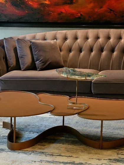 A close-up of a tufted lavender sofa and a unique, sculptural side table. The details show a commitment to unusual forms and soft, luxurious textures.