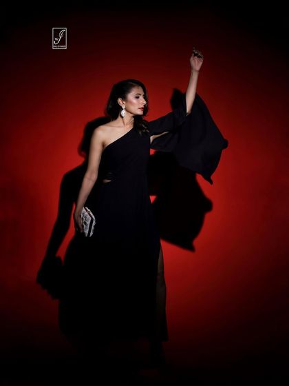 An expressive pose with an arm raised, adding movement and drama to the portrait against the vibrant red backdrop.