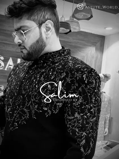 A close-up of a client wearing a black Indo-Western piece with intricate, all-over silver embroidery. The black and white photo highlights the stunning texture of the work.