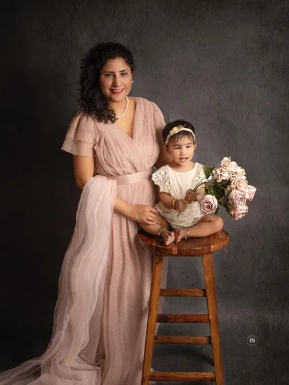 A classic mother-daughter portrait. The soft pink dress and simple dark background create an elegant and timeless image.