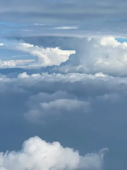 A view from a plane window showing a dramatic formation of clouds. This phone shot captures the magnificent and ever-changing landscape of the sky.