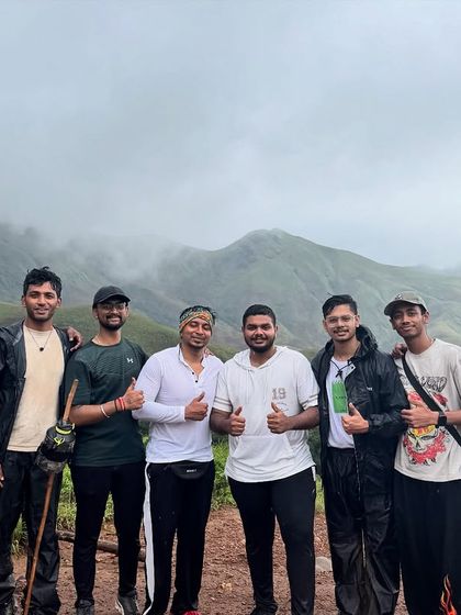 A group of friends taking a break on the trail, with the stunning Kudremukha mountains behind them.