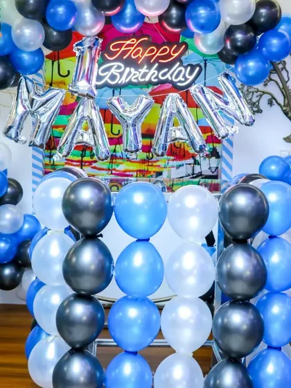A closer look at the decor for a first birthday party. The setup includes a "Happy Birthday" neon sign, foil name balloons, and a coordinated color scheme to create a polished and festive look.