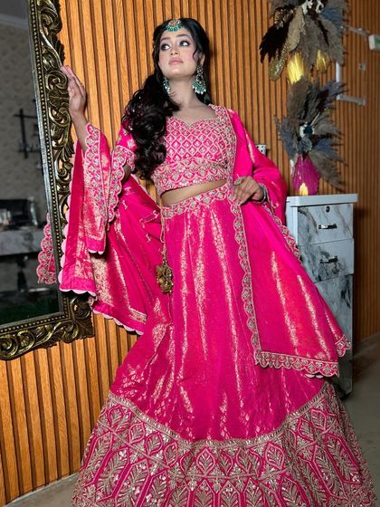 A full-length view of our hot pink Banarasi lehenga. The gold patterns on the fabric and the detailed border make it a rich and festive choice for any celebration.