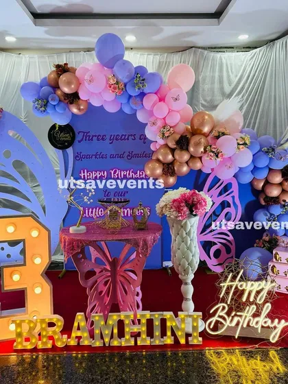 A unique butterfly-themed birthday setup with a custom backdrop and a beautiful butterfly-shaped table for the cake.