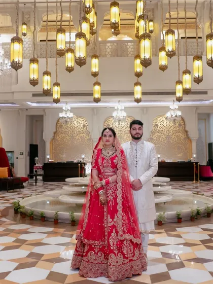 A majestic portrait of the bride and groom in a luxurious hotel lobby, showcasing the grandeur of their wedding venue.