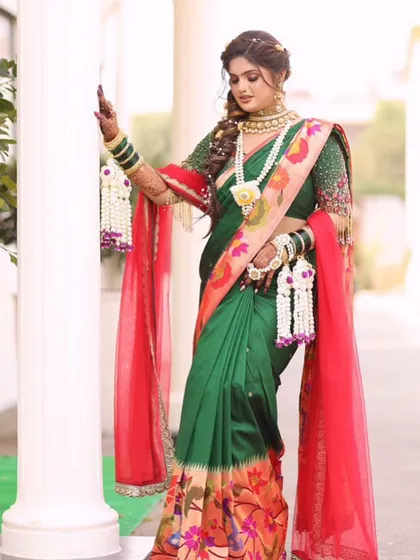 A bride posing elegantly, showcasing her full set of floral jewellery with her green and red saree.