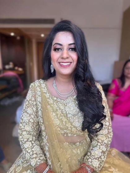 A happy and radiant bride at her Sangeet. Her gold lehenga sparkles, and her makeup is kept soft and glowing to match.
