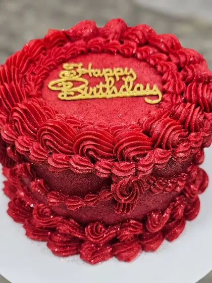 The red vintage cake topped with a golden "Happy Birthday" sign.