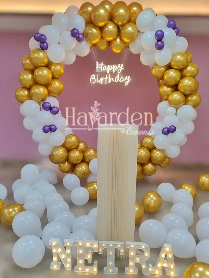 An elegant gold and white balloon ring with a 'Happy Birthday' neon sign. This setup can make any home feel like a special event venue.