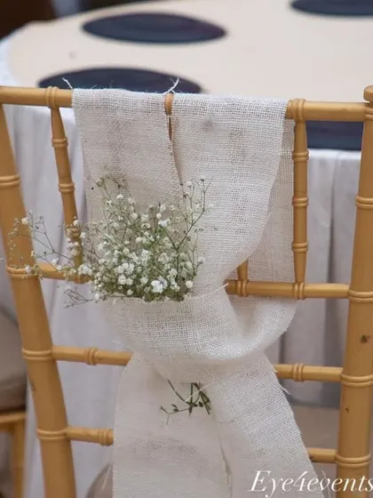 We carry the decor theme through to every element, including the seating. Here, a simple golden chair is elevated with a rustic burlap sash and a small posy of baby's breath, adding a touch of charm.