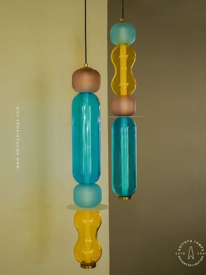 Add a playful pop of color with these kinetic sculpture pendants. Featuring stacked segments of hand-blown glass in teal, amber, and blush, these lights are a fun and artistic addition to any creative space.