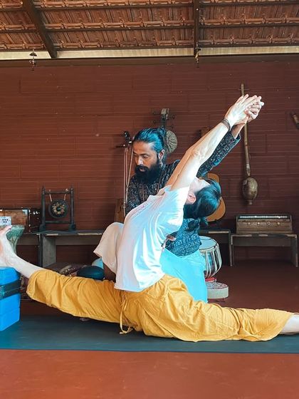 I assist a student in Hanumanasana (Monkey Pose or splits), using blocks for support. We teach how to approach advanced poses with intelligence and patience.