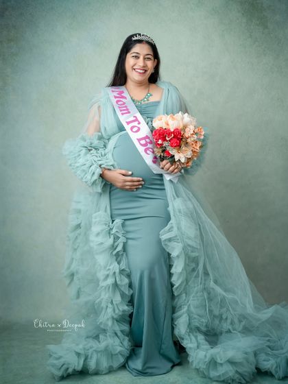 Ready for the baby shower! This mom-to-be looks radiant holding a bouquet of flowers and wearing a "Mom To Be" sash with her elegant gown.