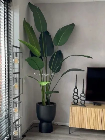 A large artificial bird of paradise plant in a stylish black pot, perfectly complementing this modern living room's decor.
