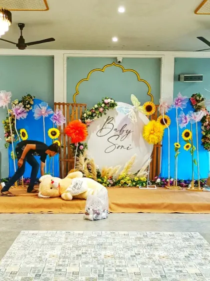 A modern naming ceremony stage being set up. This design includes a large circular backdrop, sunflower accents, and a floral ring, showing how I can work with different themes.