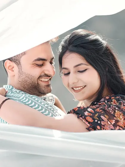 A sweet and smiling embrace under a white cloth, creating a soft and romantic feel. This is a beautiful example of a candid close-up.
