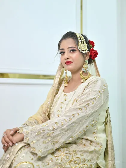 A beautiful close-up of a model in the ivory sharara set, showcasing her elegant makeup and traditional gold jewellery.