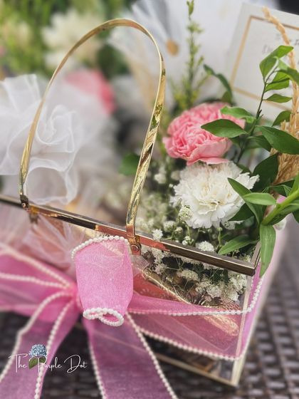 An elegant get well soon gift in a glass and gold basket, filled with delicate flowers and thoughtful items.