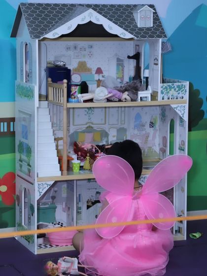 A little girl in a pink fairy costume playing with a large dollhouse. We have areas for both high-energy action and quieter, imaginative play.