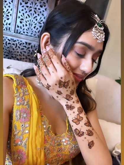 A happy client showing off her modern butterfly mehandi. This design is a favorite among guests and for parties.