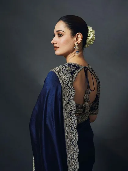 The back of this navy blue saree showcases the intricate embroidery on the blouse and the elegant tie-up detail. A timeless look for any formal occasion.