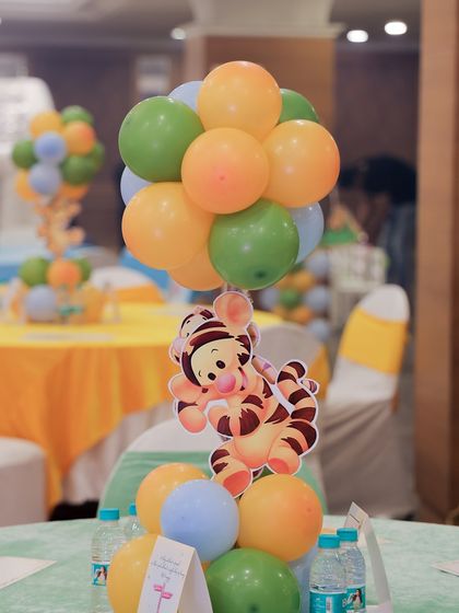 A Tigger-themed table centerpiece, with the character playfully hanging from a bouquet of colorful balloons.