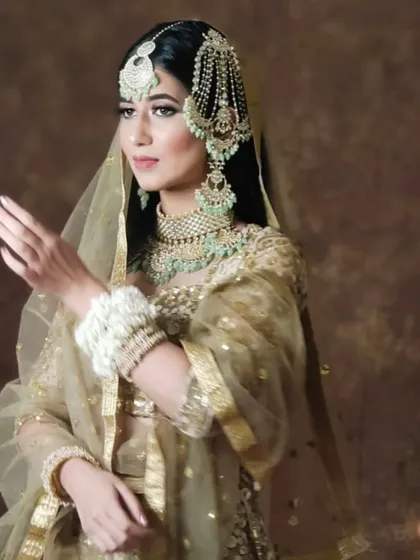 A model in a golden lehenga and mint-green jewellery, showcasing a soft and elegant look.
