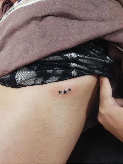 Three tiny stars on the ribcage. This is a classic minimalist design that can represent guidance, family, or personal milestones.