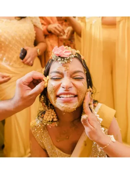 A friend playfully applies haldi to the bride's face, and her scrunched-up smile is priceless. These are the fun, candid interactions that we love to capture.