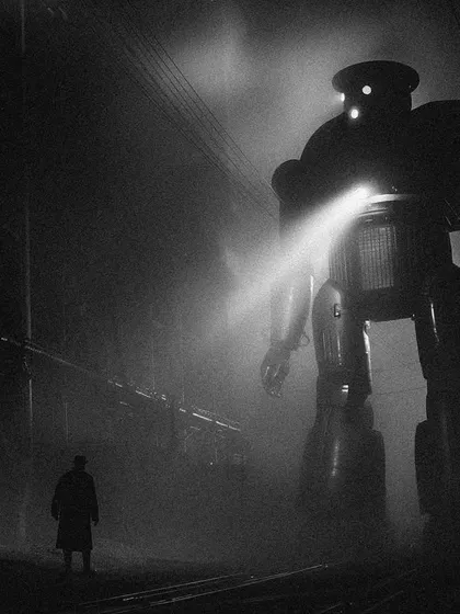 A man faces a giant, classic 1950s-style robot on a foggy night in 'Bombaytron'. This captures the 'man vs. machine' theme common in early science fiction.