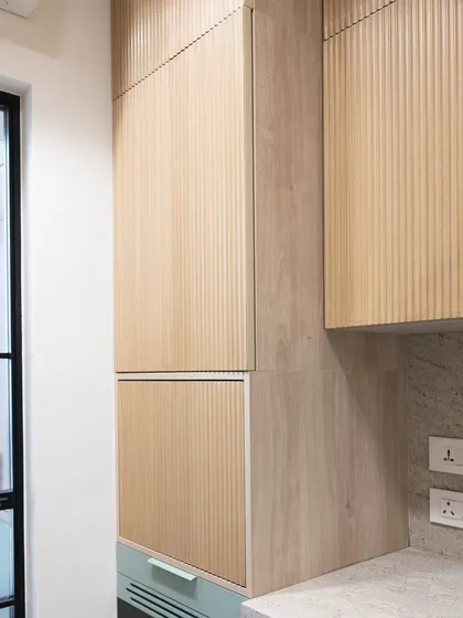 The tall, fluted wood appliance garage stands in beautiful contrast to the mint green drawers below. This pairing of texture and color is a hallmark of this fresh and simple kitchen design.