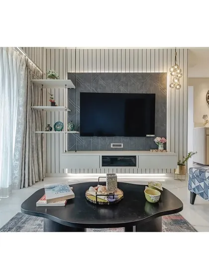 This custom TV unit is designed to be a clean and stylish focal point. The charcoal panel creates a cinematic backdrop for the screen, while the floating white console and backlit shelves provide practical storage and a place for curated decor, keeping the space uncluttered and modern.