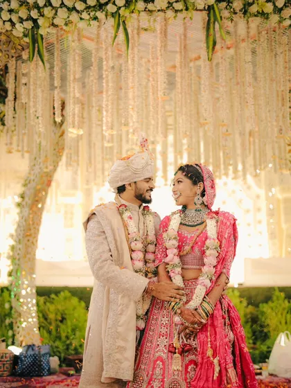 A classic wedding portrait where the couple looks at each other with love, framed by the beautiful floral decorations of their mandap.