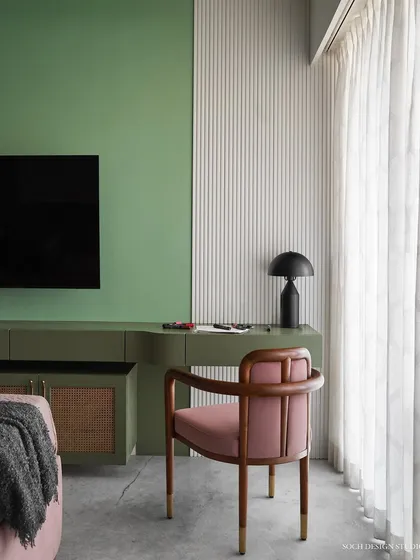 A calm and soothing study corner within the bedroom, featuring a custom green desk and a comfortable pink chair. The space is designed to be both functional for work and aesthetically pleasing.