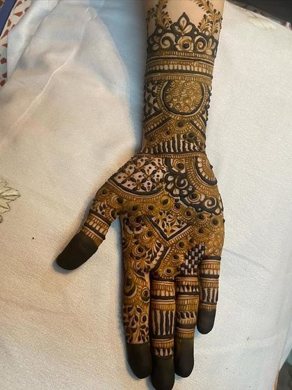 The palm of the other hand, with a large circular mandala and filled fingertips.