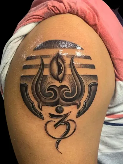 A stylized Trishul and Om symbol tattoo on the shoulder. This design combines several elements of Shiva's iconography, including his third eye, into a modern and bold piece.