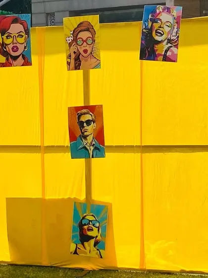 A fun and quirky pop-art themed photo wall for a Haldi ceremony. The bright yellow backdrop is decorated with colorful, retro-style portraits, creating a unique and interactive spot for guests.