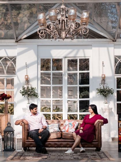 A beautifully composed shot in a glasshouse cafe. The elegant chandelier and rustic furniture create a chic, sophisticated setting for a modern couple's portrait.