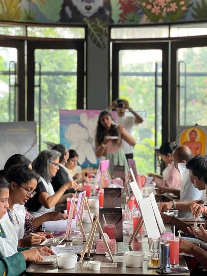 A wide shot of a texture art workshop in a beautiful, sunlit cafe. The environment is just as important as the art.