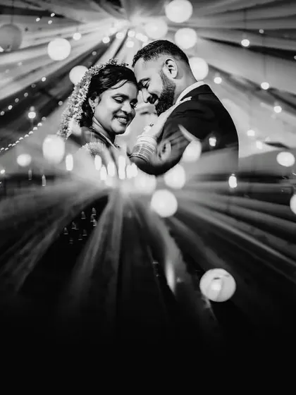 A creative black and white portrait using surrounding lights to frame the couple. This technique creates a dramatic, starburst effect that draws the eye directly to their intimate moment.