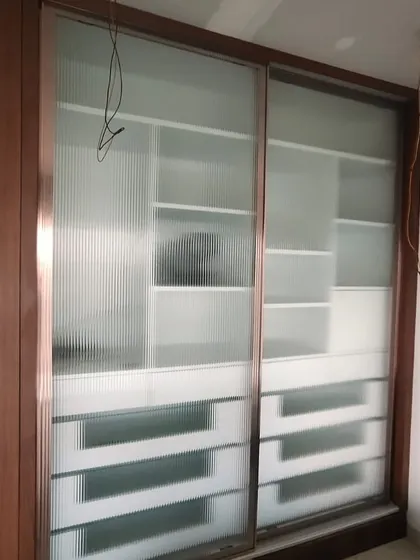 The same wardrobe with the fluted glass sliding doors installed, offering a glimpse of the storage inside while maintaining a clean look.